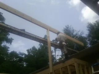 Carpenter setting a ridge beam over a new addition frame — Ice Dam Removal by Roofing Brothers in Zion Grove