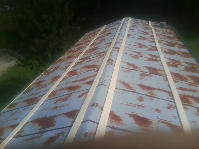 Rusted metal roof panels with new wood purlins before replacement — Storm Damage Roof Repair in Zion Grove by Roofing Brothers