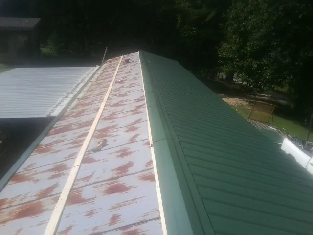 Old rusted panels beside newly installed green metal roofing — Wind Damage Roof Repair by Roofing Brothers in Zion Grove