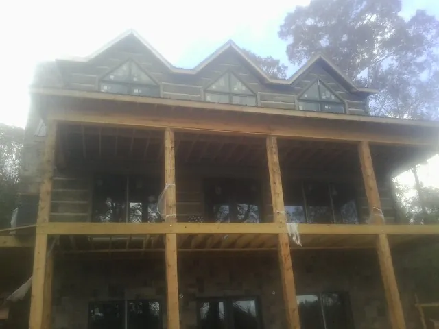 Dormers and porch framing on a large log home under construction — Roof Coating work by our crew in Zion Grove