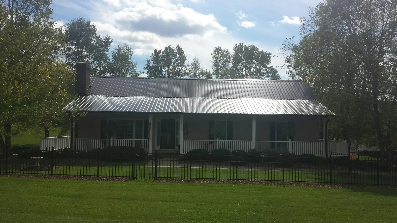 Gray metal roof on a brick ranch with a full width front porch — Gutter Guard Installation work by our crew in Zion Grove
