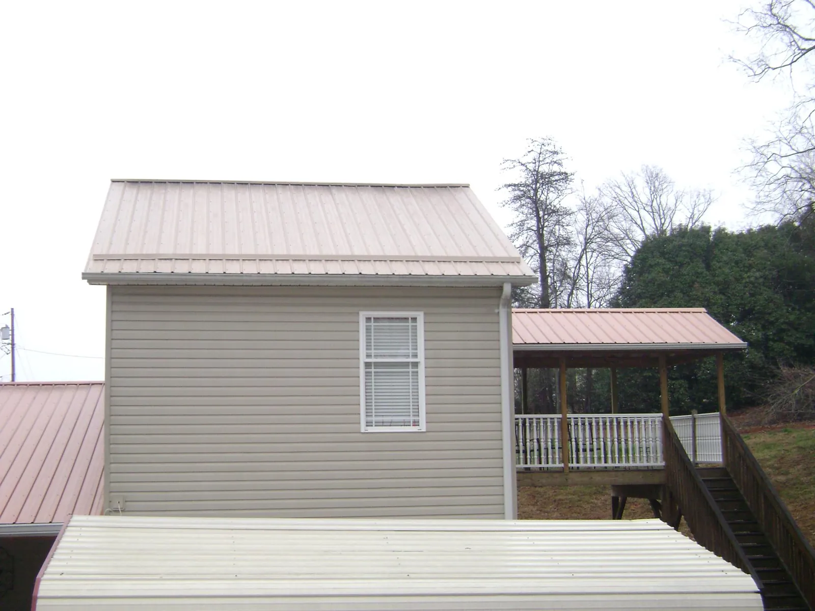 Tan metal roofs on a two story addition and attached porch, from a Roof Replacement job in Zion Grove