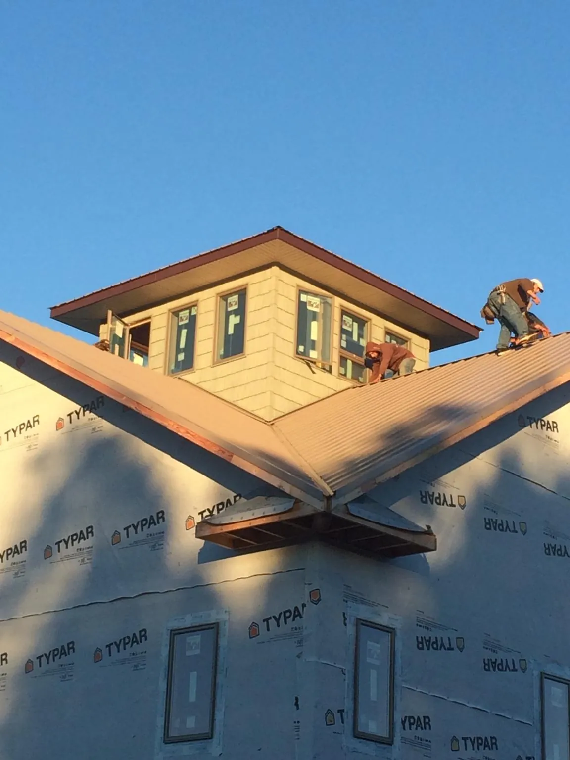 Roofers working around a rooftop cupola on a new metal roof at sunset — Roof Waterproofing in Zion Grove by Roofing Brothers